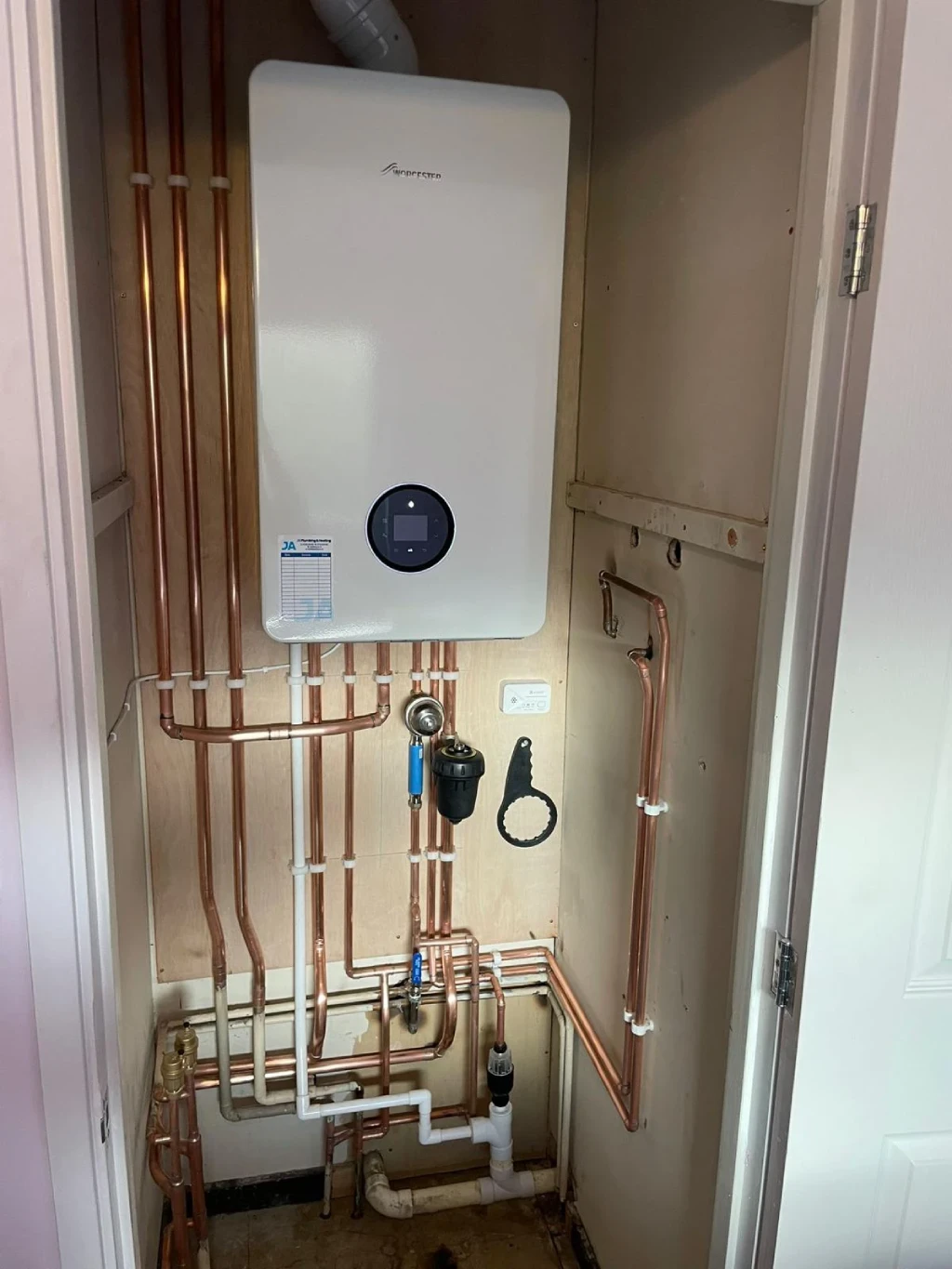 New gas boiler installation with copper piping and modern controls in a residential setting, showcasing central heating solutions.